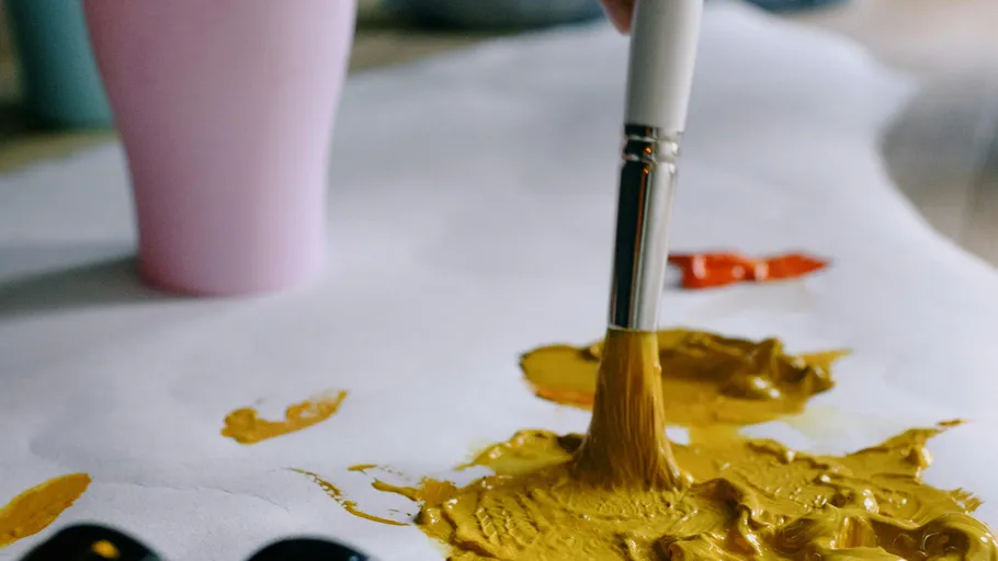 Pinsel trägt gelbe Farbe auf Papier auf.