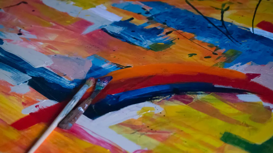 Paintbrushes on colorful abstract artwork.