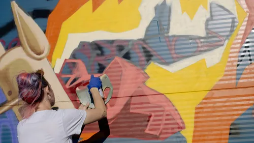 Artist painting colorful mural on wall.