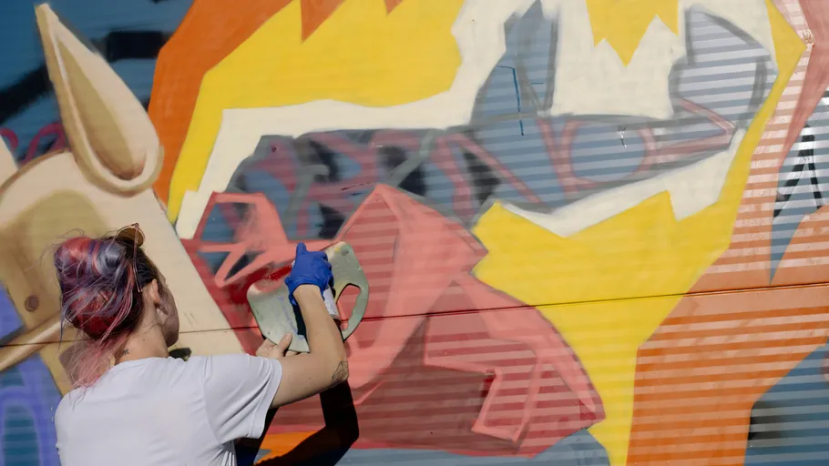 Artist painting colorful mural on wall.
