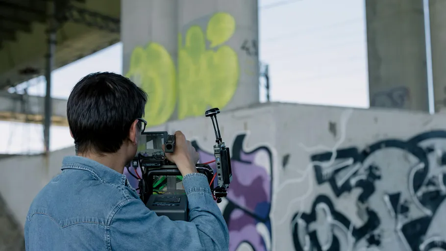Person filming graffiti under bridge.
