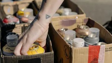 Hand wählt Sprühfarbe aus Kartons.
