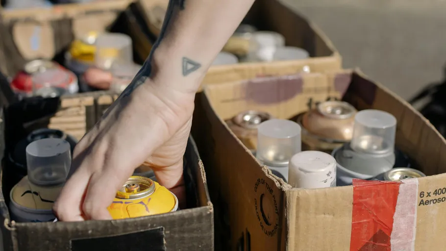 Hand wählt Sprühfarbe aus Kartons.