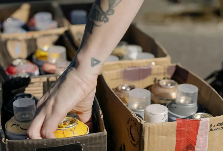 Hand selecting spray can from cardboard box.