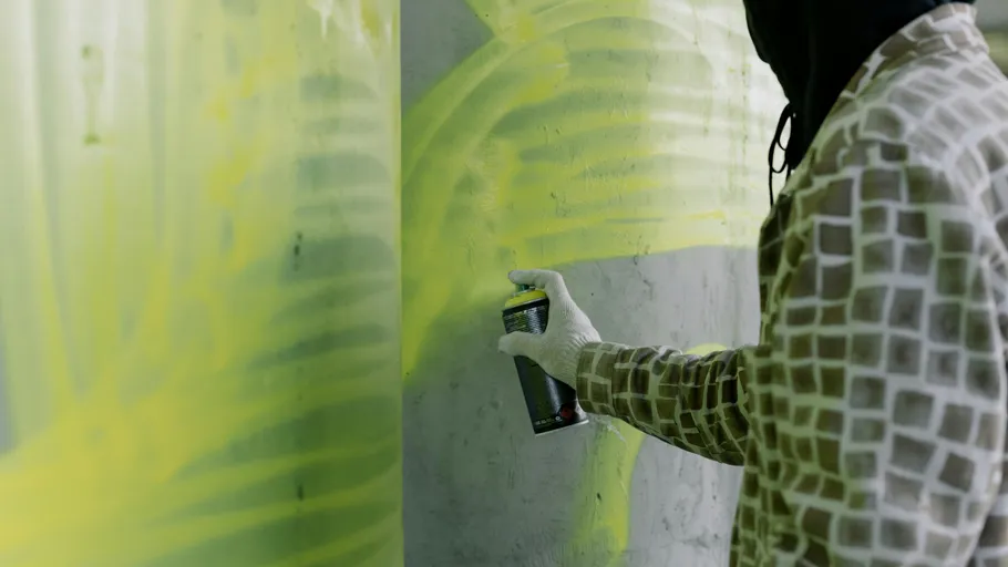 Person spray painting a concrete wall.
