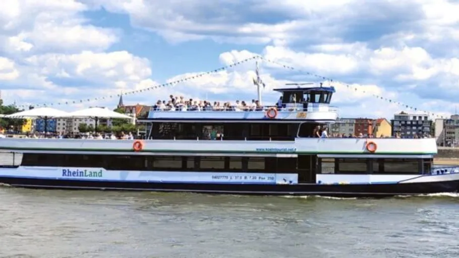 Passenger boat on river under cloudy sky.