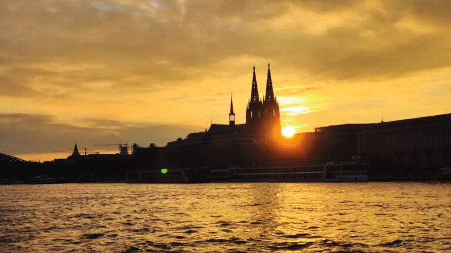 Sunset over Cologne Cathedral by the river.