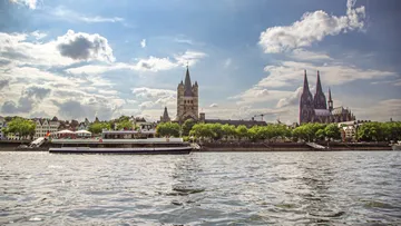 Boot fährt auf Fluss vor Kölner Dom.