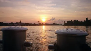 Sonnenuntergang über einem Fluss mit ferner Brücke.