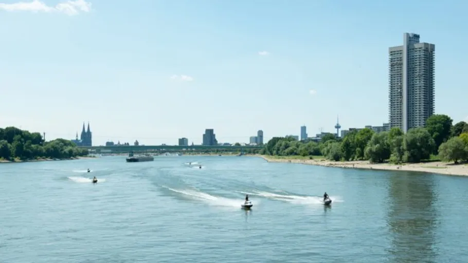 Jet skis on river, city skyline in background.