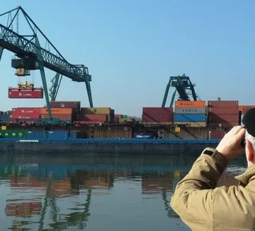 Person photographs cranes loading shipping containers.