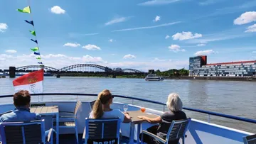 People on a boat, river view, buildings visible.