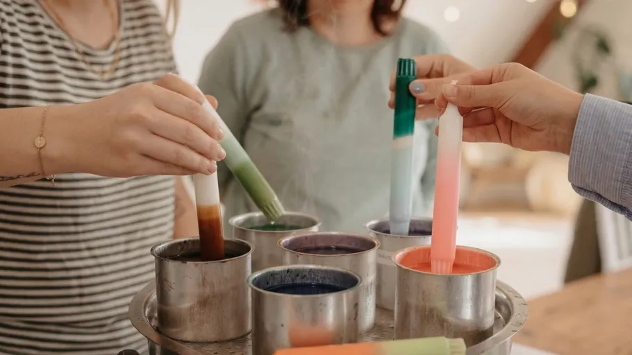 People dipping candles into colorful wax.