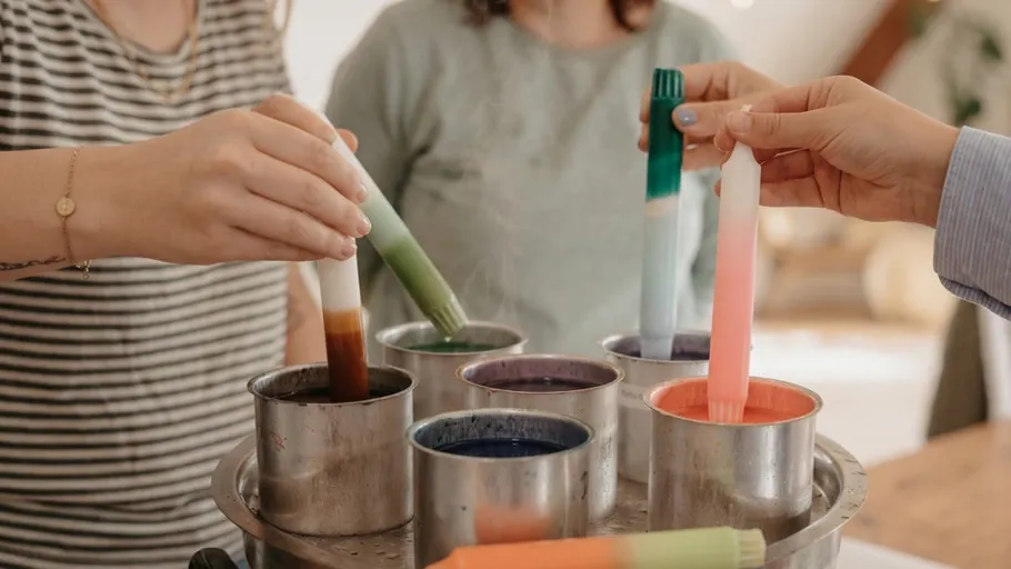 People dyeing candles in metal pots.