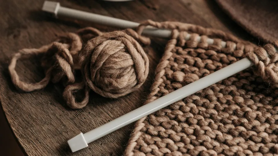 Garn und Nadeln, Strickarbeit auf Holztisch.