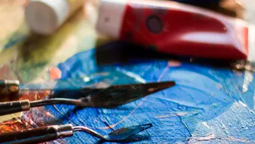 Palette knives on colorful paint surface.