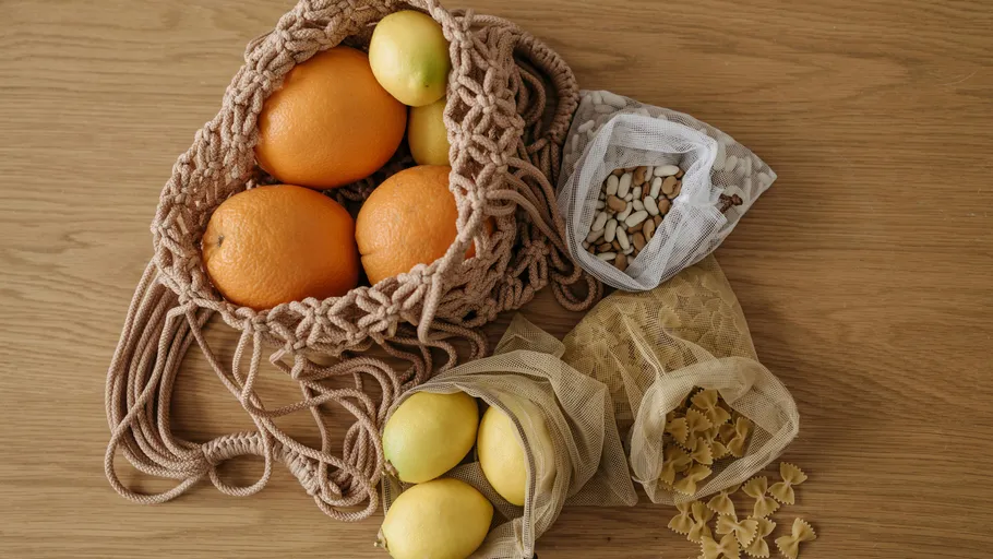 Orangen und Zitronen in Netztaschen auf Tisch.