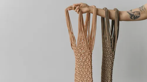 Tattooed arm holding handmade macrame bags.