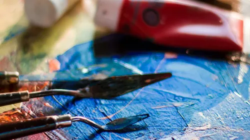 Palette knives on colorful painted surface.