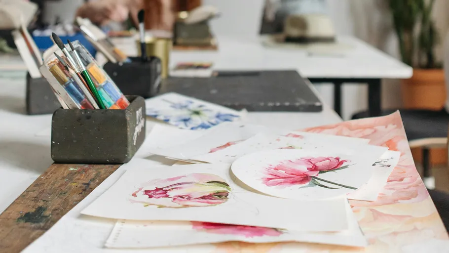 Pinsel und Blumenbilder auf einem Tisch.