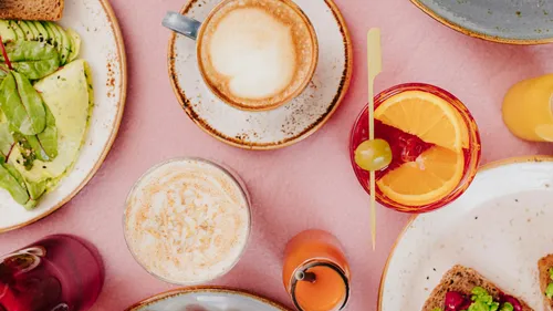 Brunch with avocado toast and drinks, pink table.