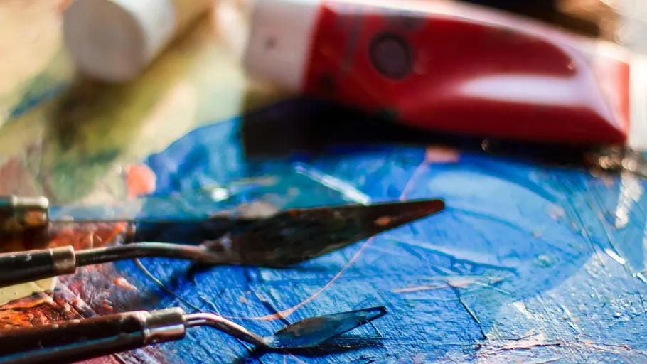 Palette knives on colorful painted surface.