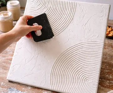 Hand creating texture on canvas with scraper.