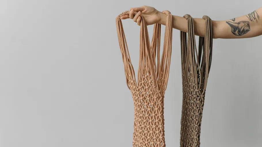 Tattooed arm holding two macrame bags.