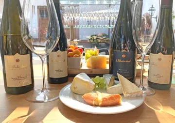 White wines and cheese platter on wooden table with glasses.
