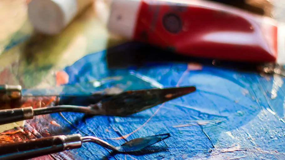 Palette knives on colorful painted surface.