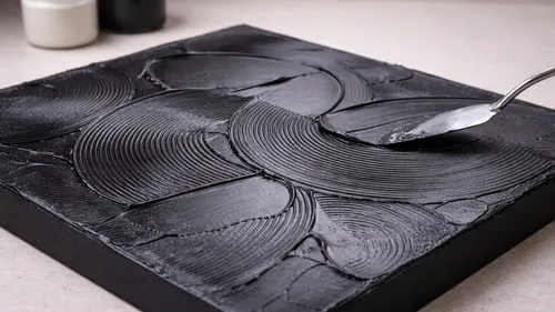 Spoon creates textured pattern on black canvas.