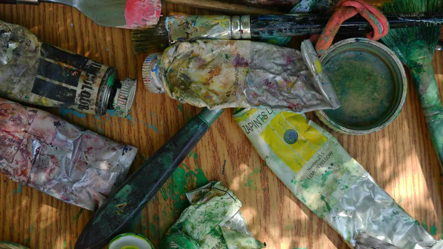 Worn paint tubes and brushes on table.