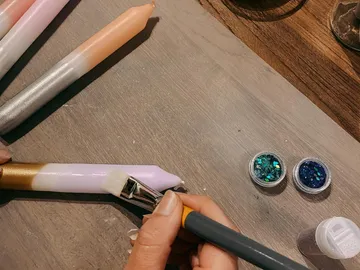 Bunte Kerzen werden mit einem Pinsel dekoriert; Tischoberfläche.