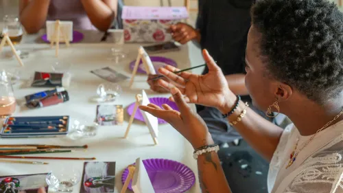 People painting at a table with supplies.