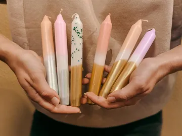 Colourful candles are held in hands, cozy background