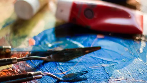 Paint tubes and palette knives on colorful canvas.