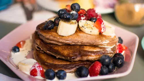 Stapel Pfannkuchen mit Obst auf Teller.