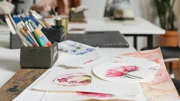 Paintings and brushes on artist's tabletop.
