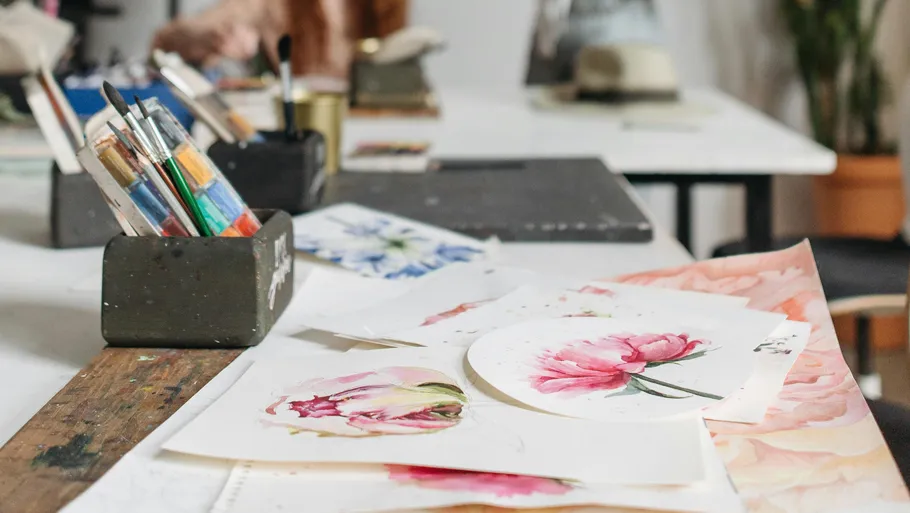 Paintings and brushes on artist's tabletop.