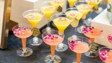 Colorful cocktails with flower garnishes on a table.