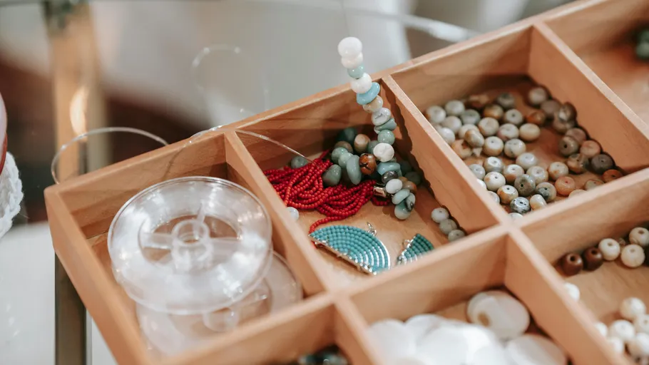 Wooden box with assorted colorful beads inside.