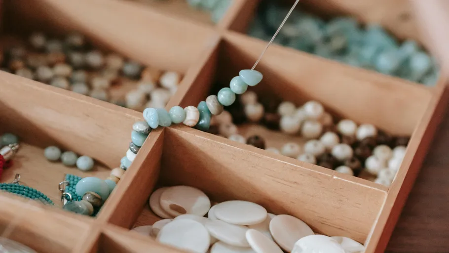 Beads being threaded in a wooden box.