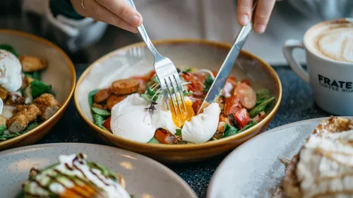 Person cutting poached egg over vegetable salad.