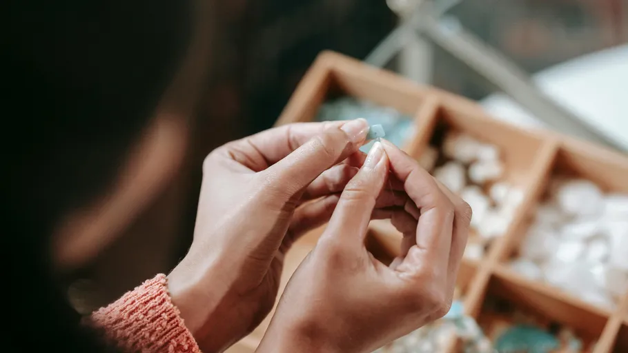 Person holding gemstone, examining it in store.