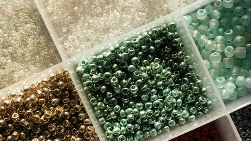 Assorted beads organized in plastic compartments.