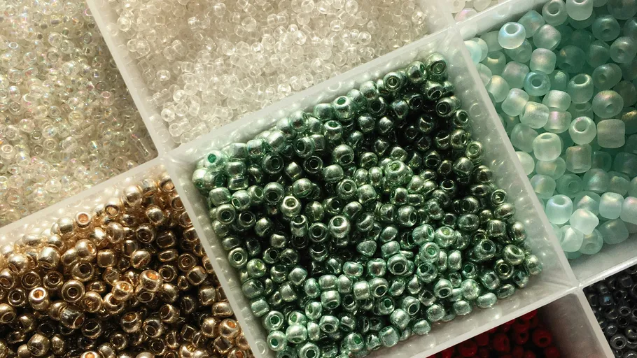 Verschiedene Perlen in Plastikfächern organisiert.