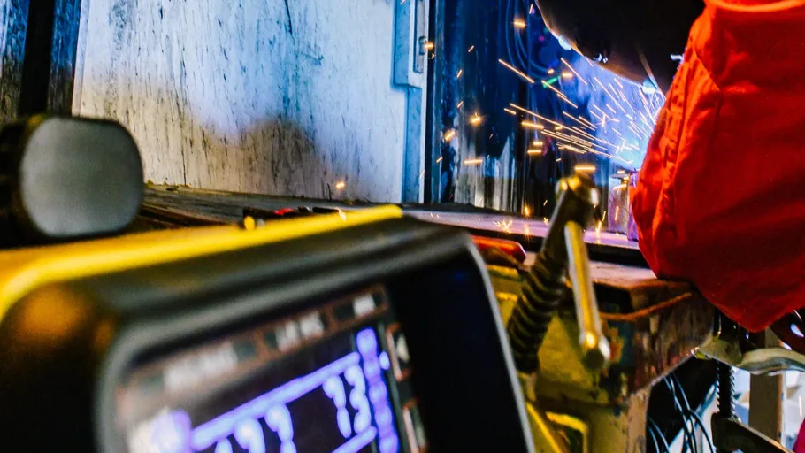 Schweißer arbeitet mit Funken in Werkstatt.