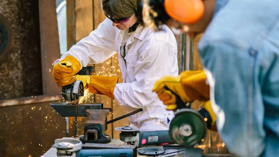 Workers using grinders, sparks flying, workshop setting.
