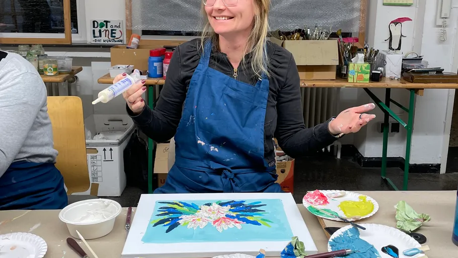 Woman smiling, holding glue with painting supplies.