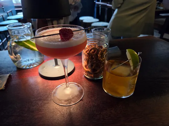Zwei Cocktails und Brezeln auf einem Bartisch.